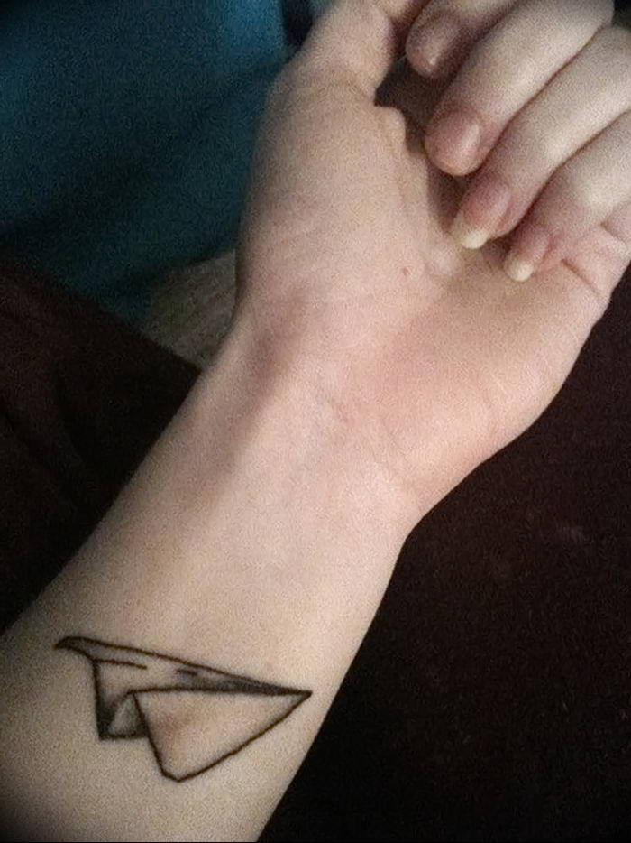 Minimalist paper plane tattoo on the tricep