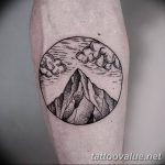 Blackwork tattoo of a mountain range with clouds inside a circular frame on the forearm.