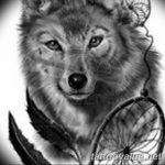 Black and grey tattoo featuring a wolf portrait combined with a dreamcatcher, including feather details. Placed on the shoulder.