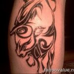 A blackwork tribal tattoo of a bull's head on a calf, featuring bold lines and geometric patterns, evoking Polynesian or Maori influences.