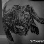 Black and grey watercolor-style tattoo of a bull's head on a shoulder, featuring loose brushstrokes and a blurred effect. An artistic and expressive tattoo design.