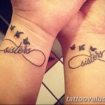 Matching infinity symbol tattoos with 'sisters' lettering and birds flying around, wrist placement, black ink, friendship tattoo.