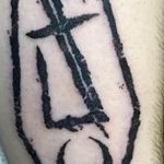 Simple black tattoo of a coffin with a sword inside and a crescent moon below, placed on the arm.