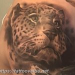 Black and grey realism leopard face tattoo on a shoulder, showcasing incredible detail in the eyes and fur. A stunning tattoo art piece.