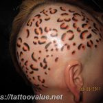 Unique leopard spot tattoo design covering the scalp, featuring black and orange spots on a pale skin tone. A bold and unconventional tattoo placement.