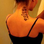 Small, black paw prints tattooed along the back of the neck, creating a subtle and charming design. A minimalist tattoo idea for animal lovers.