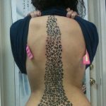 Full spine tattoo featuring leopard print pattern, black ink, long vertical design, animal print, bold tattoo.