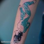 Colorful tattoo of a mermaid with a turquoise tail and grey head, side profile, flowing hair, placed on the forearm.