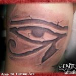 Black and grey tattoo of the Eye of Horus appearing to emerge from cracked skin, placed on the forearm.