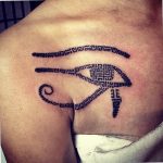 Intricate Eye of Horus tattoo on the upper chest, geometric patterns, black ink, showcasing ancient Egyptian symbolism and modern design.