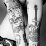 Black and grey tattoo sleeve featuring a heart with an arrow, a swallow, a skull, a pistol, and script with 'C'est la Vie' on the forearm.