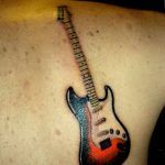 Colorful tattoo of an electric guitar with a vibrant burst effect on the shoulder.