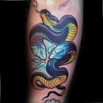 Neo-traditional tattoo of a blue and yellow snake coiled around a fractured crystal, with bold outlines and vibrant colors on the arm.