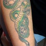 Traditional style green snake tattoo wrapping around a forearm, bold lines, vibrant color, classic tattoo art.
