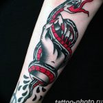 Bold American Traditional tattoo featuring a snake coiled around a hand, with red accents. A classic forearm tattoo with strong lines and vibrant colors.