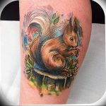 Vibrant watercolor style squirrel tattoo on the calf, featuring a mushroom, leaves, and a soft, blended aesthetic.