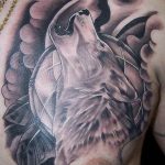 Large black and grey wolf head tattoo on the chest, with detailed fur and intense eyes. A powerful and realistic animal tattoo design.