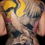 Detailed Japanese-style back tattoo featuring a crane, moon, cherry blossoms, and a traditional building. A large and intricate ink idea.