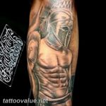 Black and grey tattoo of a Spartan warrior's torso and helmet, detailed shading and strong lines on the forearm.
