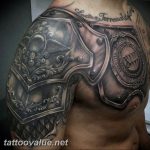 Detailed black and grey tattoo of a Roman centurion's armor on the chest and shoulder, featuring ornate designs and a shield.