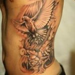 Large black and grey realism dove tattoo on the side, with floral elements and dramatic shading. A bold tattoo design for a striking visual impact.