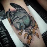 Neo-traditional tattoo of a pigeon perched on a branch with leaves, on a calf. Bold lines, vibrant colors, and illustrative style.