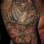 Detailed black and grey tattoo featuring a dove, a cross, rosary beads, and a veiled face, on the shoulder. Highly detailed and religious in theme.