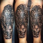 A detailed black and grey snow leopard tattoo covering a full sleeve, showcasing the animal's head and upper body with intricate fur patterns.
