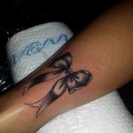 Grey bow tattoo on the wrist, showcasing a simple and elegant tattoo design. The style is realistic with smooth shading, ideal for a subtle look.