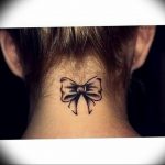 Small black outline bow tattoo on the back of the neck, minimalist style, delicate tattoo design, feminine ink.