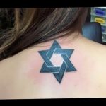 Small, grey-shaded Star of David tattoo on the back of the neck, a subtle and personal expression of Jewish faith and identity.