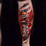 Colorful biomechanical tattoo on a calf, depicting a futuristic cybernetic implant with exposed wires and metallic components.