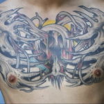 Large biomechanical tattoo covering a man's chest, depicting a skeletal structure interwoven with metallic gears and red accents. Black and grey realism style.