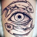 Blackwork tattoo featuring fish forming an eye, intricate linework, and abstract design on the forearm.