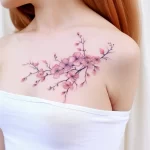 Watercolor-style cherry blossom tattoo on the shoulder, featuring delicate pink blooms and branches, ideal for a feminine design.