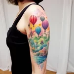 A whimsical watercolor tattoo on the upper arm, featuring hot air balloons, diamond-shaped kites, and a serene landscape, creating a dreamy aesthetic.