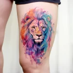 Thigh tattoo featuring a colorful watercolor lion portrait with a flowing mane and dripping ink effects, showcasing a vibrant and dynamic style.