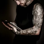 A person with tattoos browsing a FAQ section about t c da afd e adfdc 16.12.2023 tattoovalue.net 056
