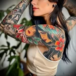 A colorful Neo-Traditional tattoo featuring a woman's face, flowers, and bold outlines, covering the shoulder and upper arm of a woman.