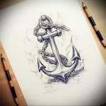 Black and grey tattoo sketch of an anchor with a chain, surrounded by stylized waves, showcasing a traditional nautical aesthetic.