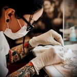 Close-up shot of a tattoo artist with protective gear, meticulously applying ink to a client's skin, showcasing traditional Japanese tattoo art.