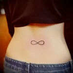Small black ink infinity tattoo on the lower back, minimalist style, clean lines, simple design, feminine tattoo, hip placement.
