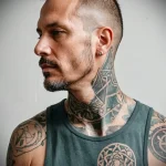 Black ink geometric tattoo on a man's neck and shoulder, featuring sharp angles and abstract shapes. A striking and modern tattoo design with a strong visual impact.