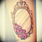 A watercolor-style tattoo on the arm featuring a vintage mirror with pink roses, showcasing soft colors and delicate lines.